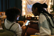 © BONNINSTUDIO/Stocksy - Black girlfriends using smartphone together at movie night