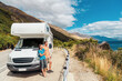 © Maridav - Motorhome RV camper van road trip on New Zealand. Young couple on travel vacation adventure. Two tourists looking at Lake Pukaki and mountains on enjoying view and break next to rental car