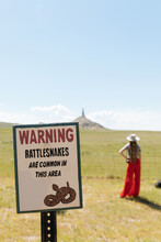 Woman In Red Pants Stand In Front Of Chimney Rock In Nebraska With Rattlesnake Sign