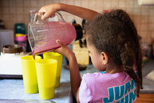 Young Girl Pouring Blended Smoothies Into Cups