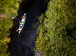 © JP Danko/Stocksy - People using canoe to travel narrow waterway between green shore