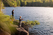 © JP Danko/Stocksy - Boys on fishing trip vacation stand on shore and cast lines into