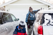 Father Sweeps Snow Off A Vehicle Roof Onto Son 