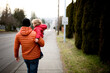 © Jennifer Bogle/Stocksy - Father in jacket carries son down sidewalk