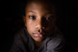 © Jennifer Bogle/Stocksy - Dark portrait of serious young boy
