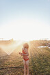 © Claira Whipp/Stocksy - girl playing in sprinkler
