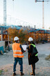 © Jimena Roquero/Stocksy - Back of Woman engineer and construction worker supervising the development of a building in construcion.