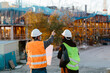 © Jimena Roquero/Stocksy - Back of Woman engineer and construction worker supervising the development of a building in construcion.