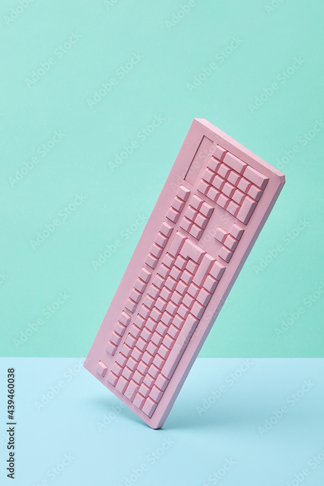 Vertically balancing papercraft pink keyboard. Stock Photo | Adobe Stock