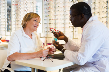 Mature woman client talking with ophthalmologist during choosing glasses