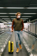 © Alina Hvostikova/Stocksy - Male traveler with suitcase riding airport escalator during pandemic