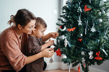 Mom And Baby Adding Decorations To Christmas Tree