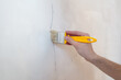 Construction man worker repairing a crack wall of a home, plastering cement on wall. Builder applying white cement to a crack in a wall with a putty knife.