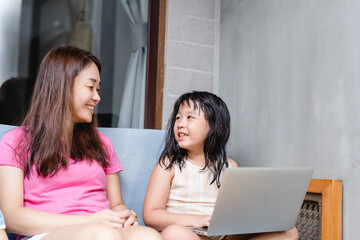 Wall Mural - Happy asian mother and kid girl with laptop computer at home.teacher mother is teach her children during coronavirus covid19 lockdown.Education, Online learning, back to school.School kid.Homeschool.