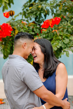 Laughing Asian Couple Embrace Under Tree With Bright Orange Blossoms
