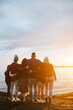 © Rob and Julia Campbell/Stocksy - Family staring into the sunset together on rocky beach.