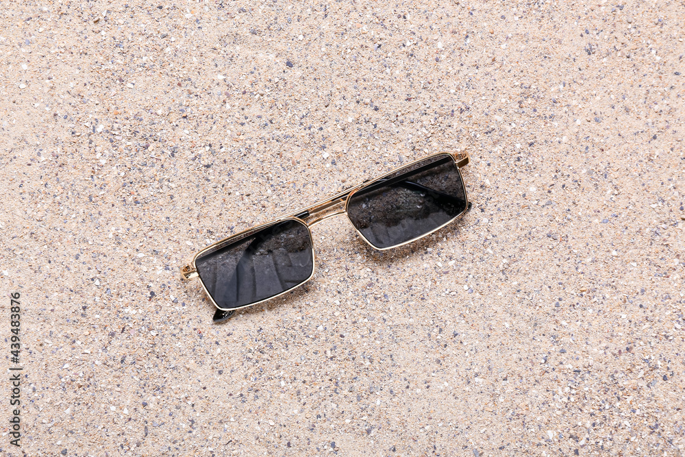 Stylish beach sunglasses on sand