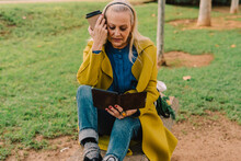 Senior Woman Reading An Ebook  At Park