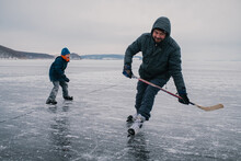 Father And Son Ice Skating On The Frozen River