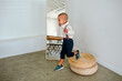 © Erin Brant/Stocksy - Young bi-racial boy jumps from jute cushion onto floor