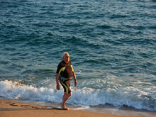 Aged Man Walking By The Shoreline With The Watersports Suit