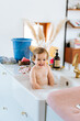 © Melissa Milis Photography/Stocksy - Baby girl sitting in kitchen sink for a wash