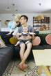© Melissa Milis Photography/Stocksy - father sitting in living room with two kids