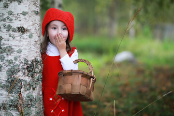 Wall Mural - A little girl in a red hat and dresses is walking in the park. Cosplay for the fairytale hero 