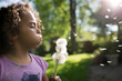 © Jennifer Bogle/Stocksy - Girl blows dandelion seeds in back yard