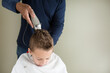 © Jennifer Bogle/Stocksy - boy ducks head as father clippers back of his head