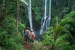 © Alexander Grabchilev/Stocksy - Tourists exploring a waterfall in the jungle