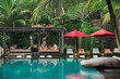 © Alexander Grabchilev/Stocksy - couple of tourists relaxing by the pool in a resort in the tropics