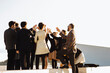 © sofie delauw/Stocksy - Unrecognizable stylish friends with wine celebrating festive event on rooftop
