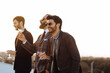 © sofie delauw/Stocksy - Cheerful stylish men with alcoholic beverages talking during party outdoors