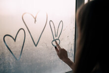 Young Woman Drawing Hearts On The Window