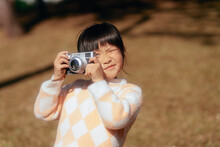 Asian Little Girl Taking Pictures With Camera Outdoors
