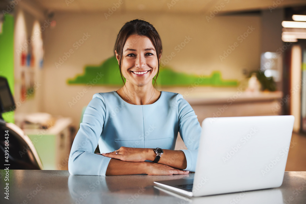 Happy attractive brunette virtual assistant working at the laptop in conference room - obrazy, fototapety, plakaty 