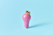© Yaroslav Danylchenko/Stocksy - Pink light bulb with crown
