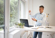 © epiximages - Businessman with blue shirt stands by high table and works with windmill model and is happy