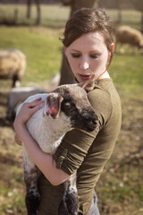 young woman holding a cute lamb, affectionate breeding and care