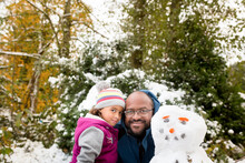 Smiling Father And Daughter With Snowman