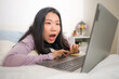 © TheVisualsYouNeed - young beautiful Asian woman working with laptop on bed -  lifestyle home portrait of young pretty and happy Japanese student girl networking excited with computer