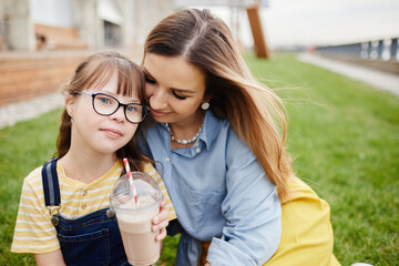 Wall Mural - Portrait of loving mother and daughter with down syndrome embracing outdoors together, copy space