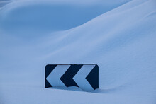 Road Sign Of Sharp Turn Buried In Snow