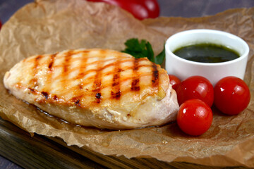 Grilled chicken breasts with ingredients on dark wooden table closeup view