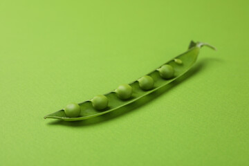 Green pea pod with seeds on green background