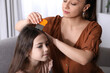 © New Africa - Mother using nit comb on her daughter's hair indoors. Anti lice treatment