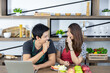 Lovely young Asian couple in modern kitchen, lover is smiling and eating fresh fruits, healthy food together on wooden table in holidays weekend.