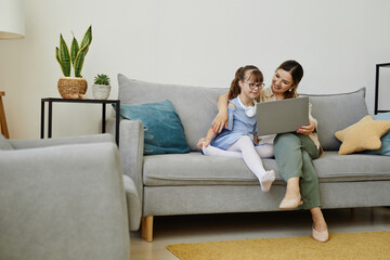 Wall Mural - Portrait of young woman using laptop with cute girl with disability, copy space