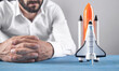 © andranik123 - Caucasian businessman with a toy rocket at office.